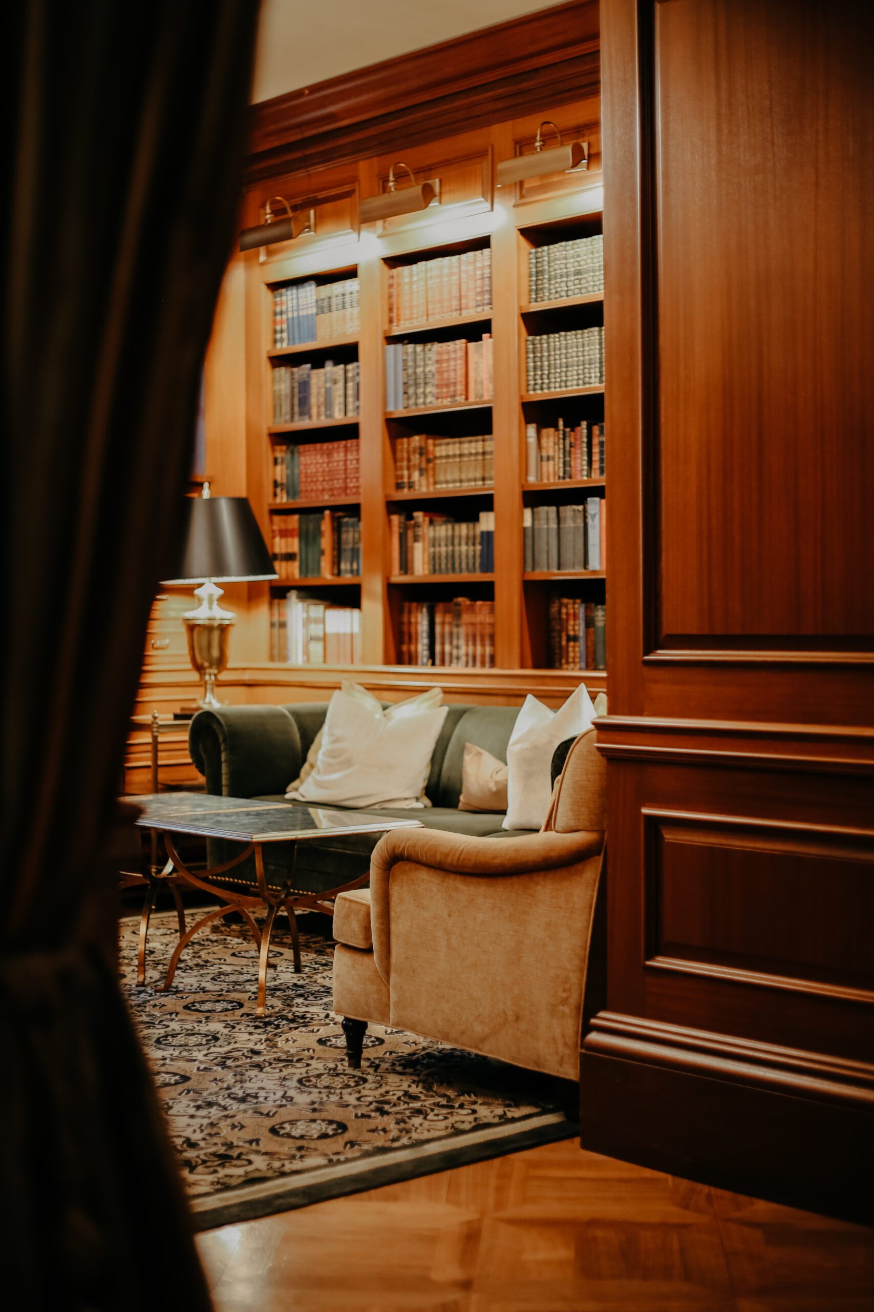 Elegant wood-paneled library with floor-to-ceiling bookshelves and a cozy upholstered armchair.
