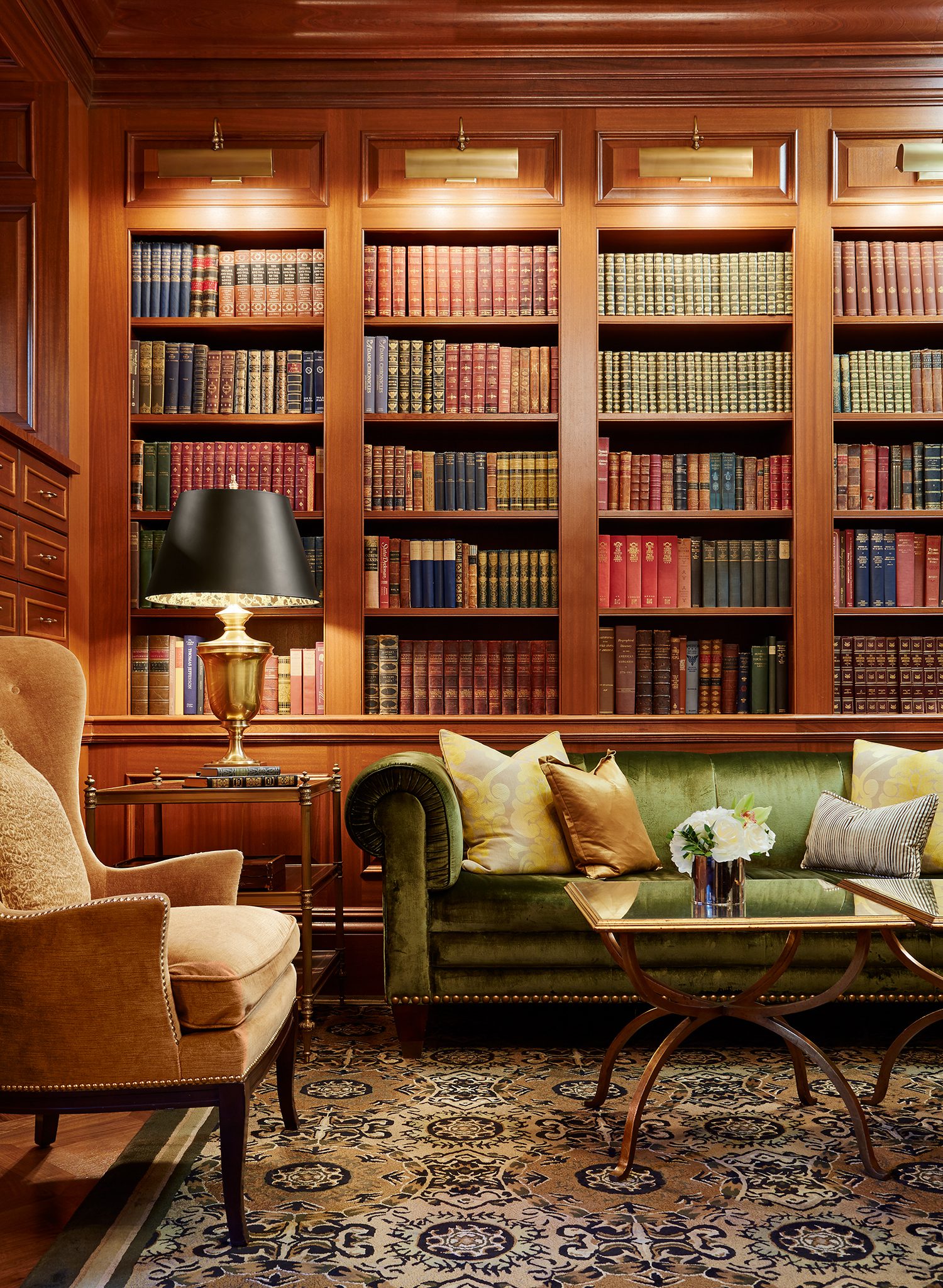 Elegant lounge with bookshelves, sofa, and table lamp