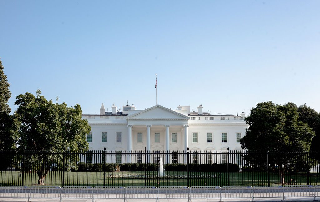 The White House exterior with front lawn, trees and black iron fence in Washington DC