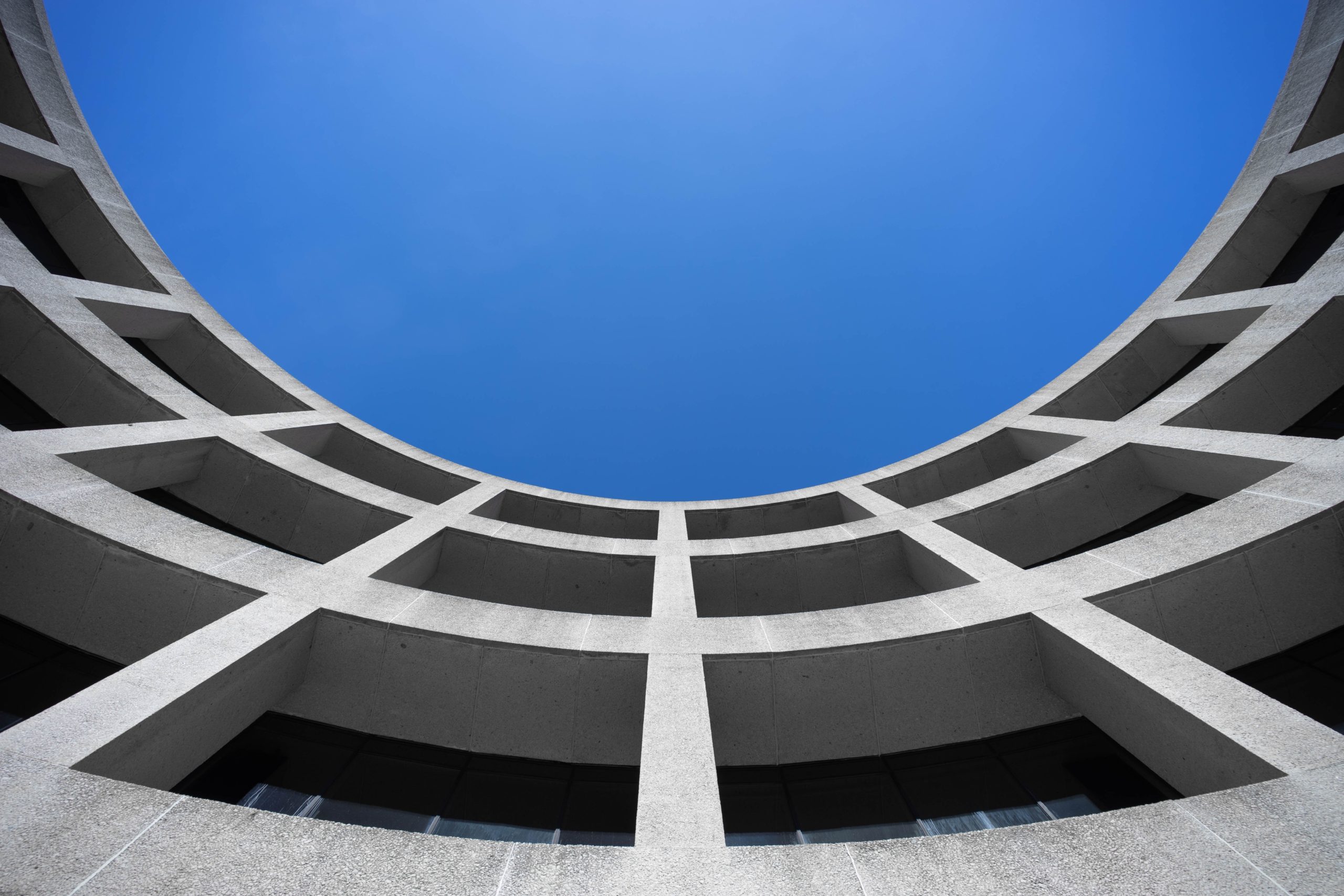 Curved concrete facade frames a vivid blue sky in a striking architectural view