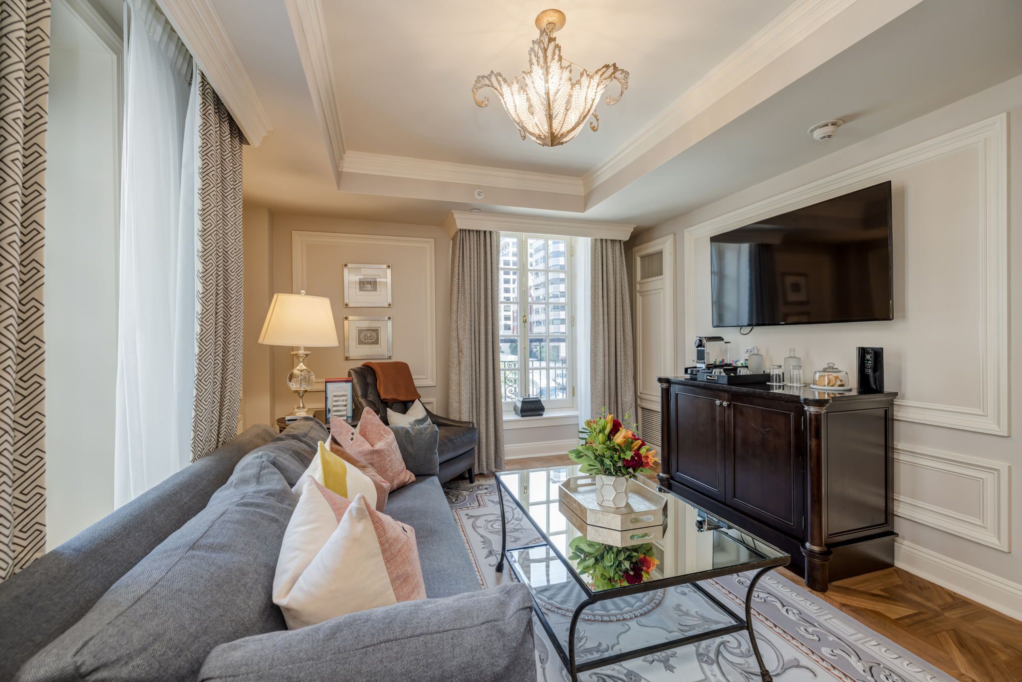 Elegant hotel suite living room with sofa, chandelier, and city view